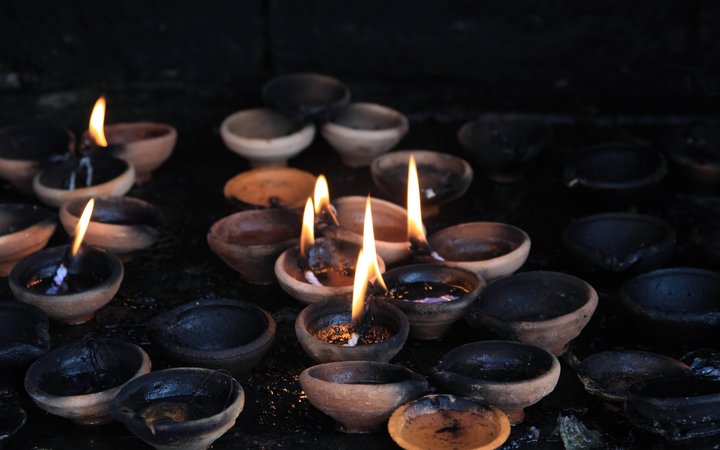 Photo of offering lit candles in dark buddhist sacrificial altar