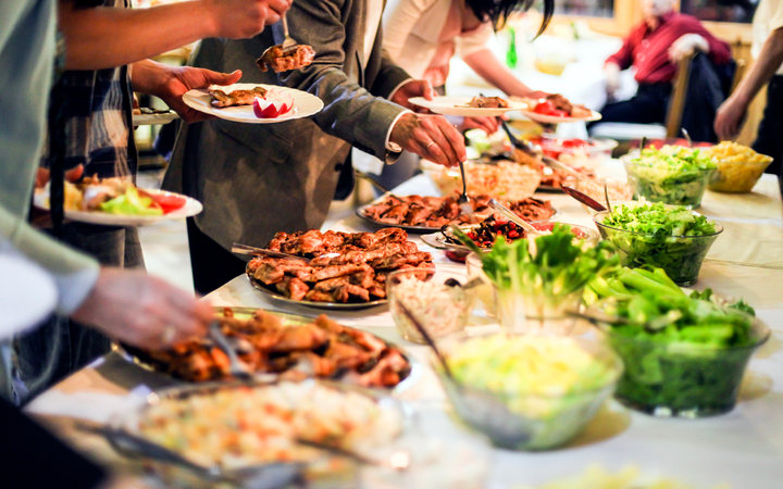 Group of unrecognizable people picking food from a buffet